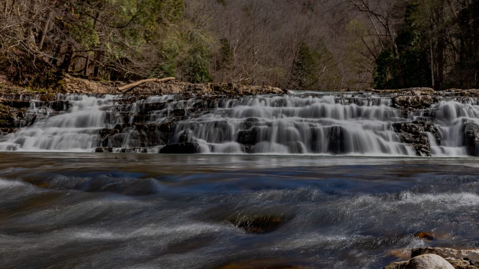 A waterfall cascading over rocks in a forested area.