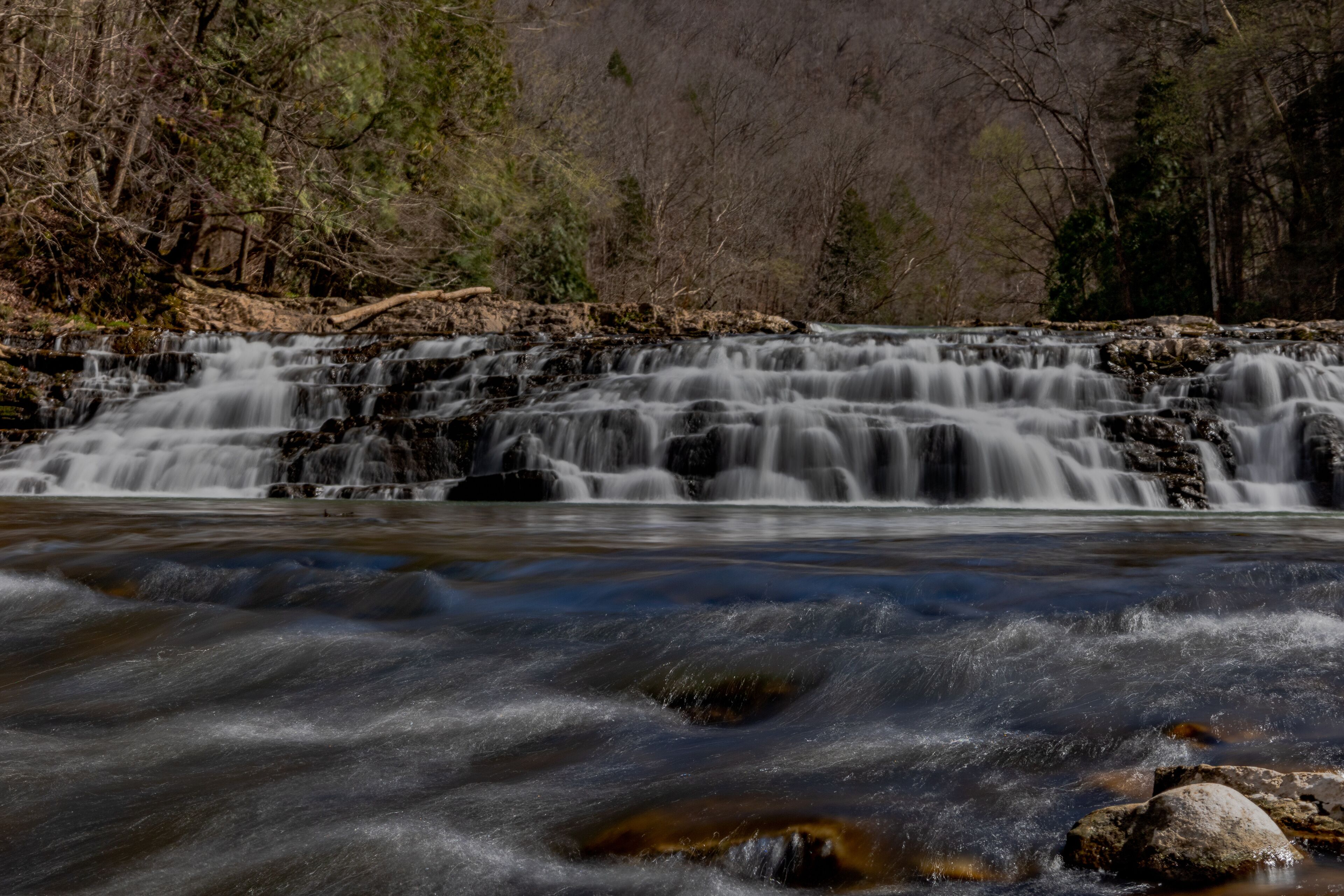 A waterfall cascading over rocks in a forested area.