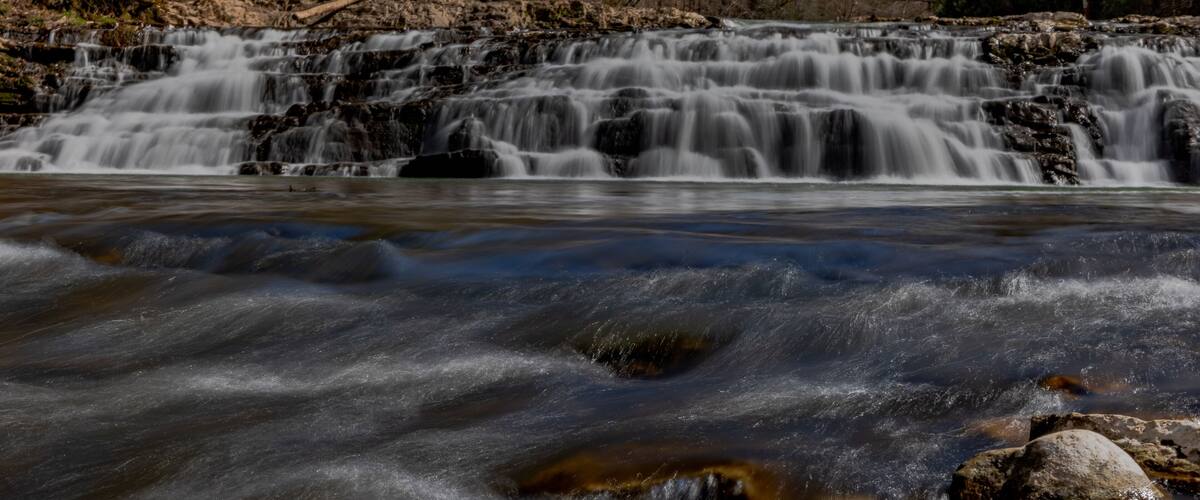 A waterfall cascading over rocks in a forested area.