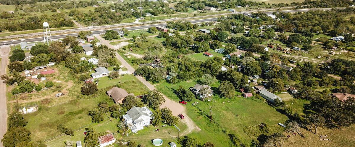 An aerial view of a rural town with scattered houses, a water tower, and a highway.