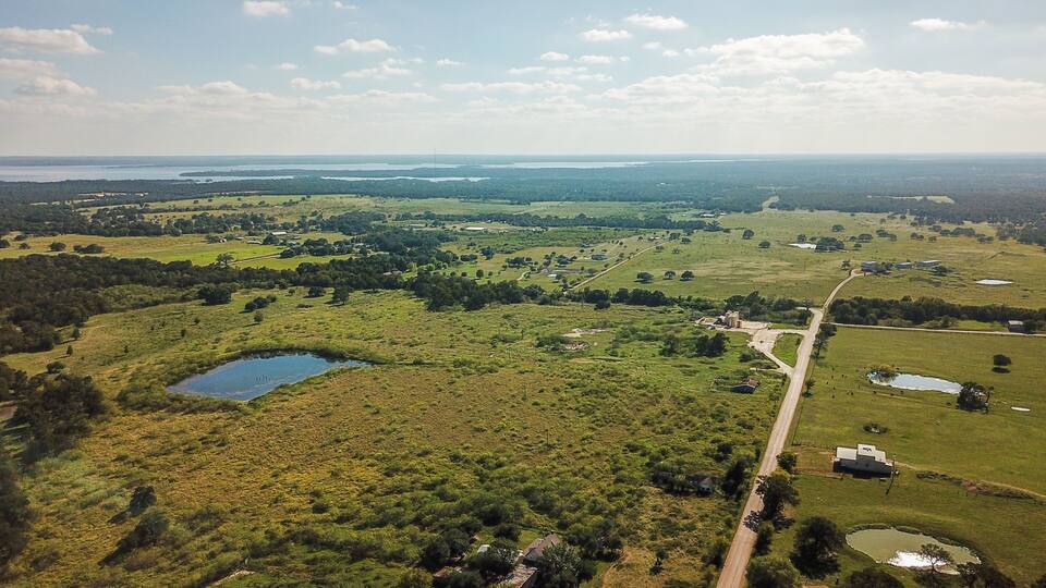 An aerial view of a rural landscape with fields, a small lake, and scattered buildings.