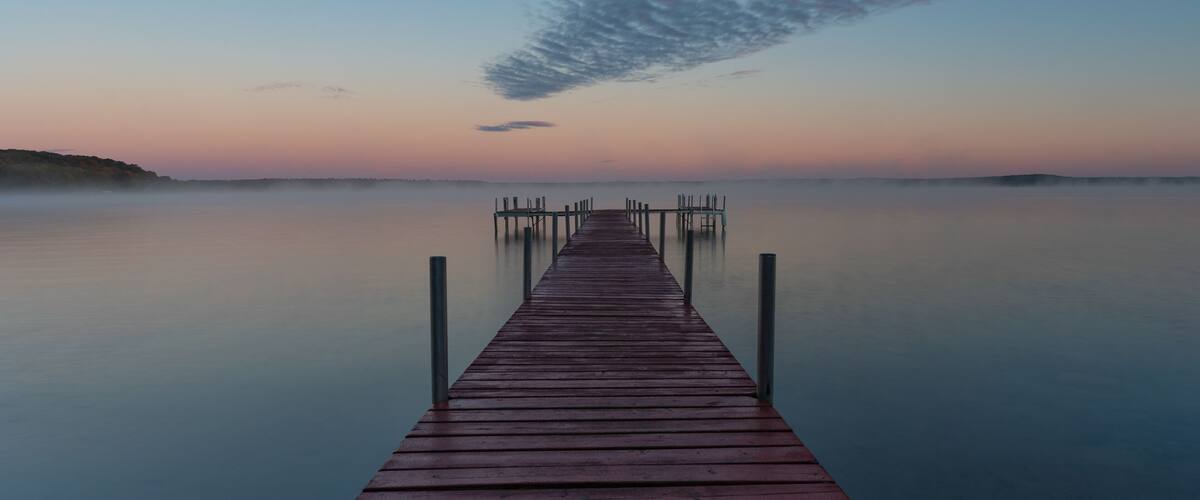 A wooden pier extending into calm waters at dusk.