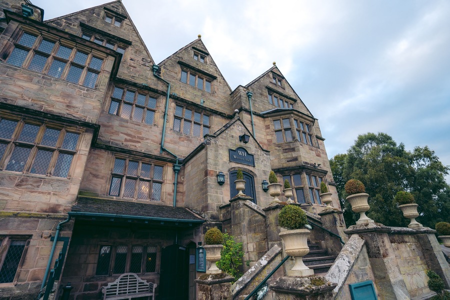 Un edificio histórico de piedra con múltiples ventanas, un cartel que dice "Westminster Hall" y una escalera con urnas decorativas.