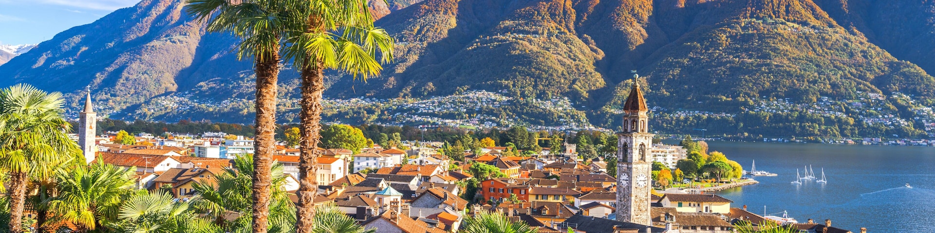 Un pueblo costero con palmeras, una iglesia y montañas al fondo.