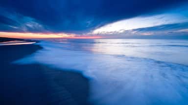 A beach at sunset with a dramatic sky.