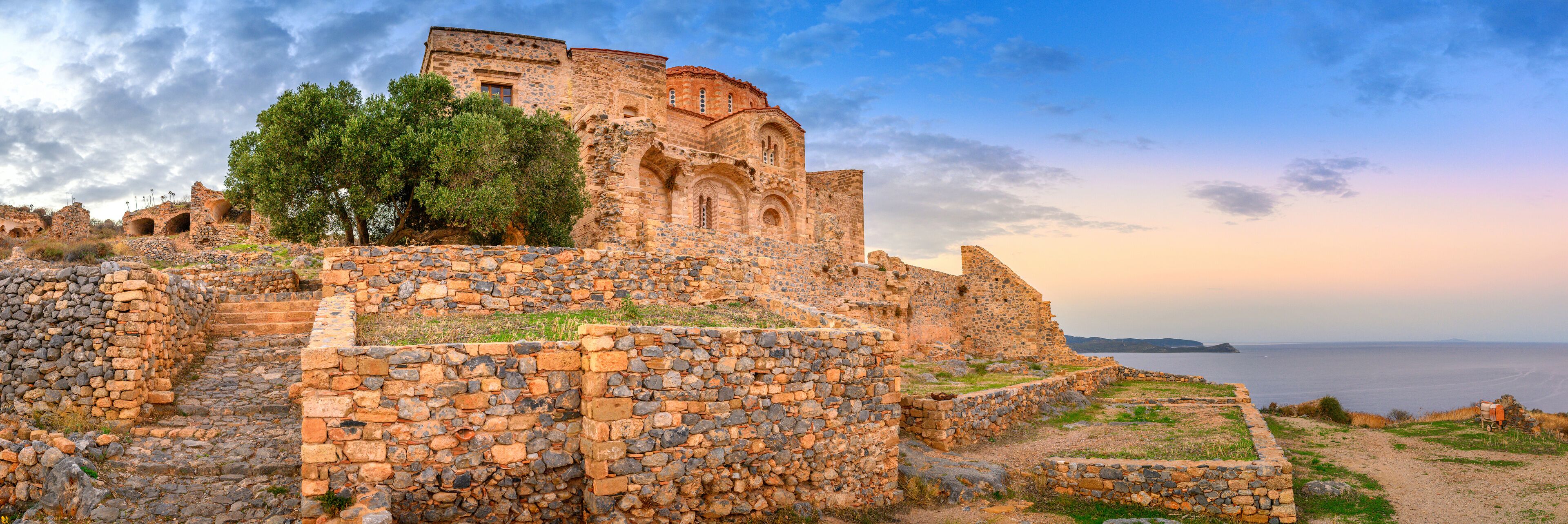 Ancient stone ruins with a view of the sea.