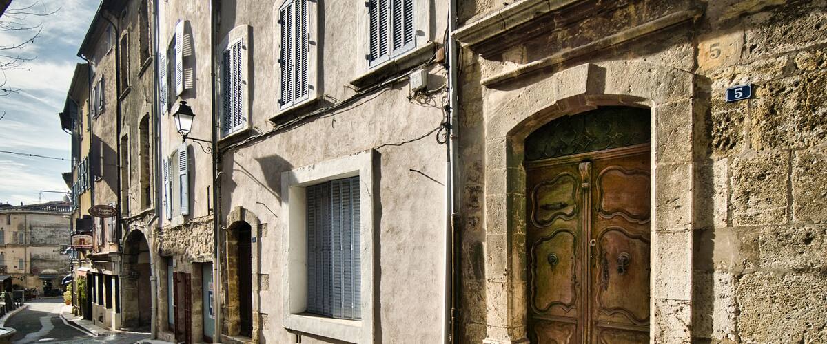 A narrow street with old buildings, a large wooden door, and a number '5' sign.