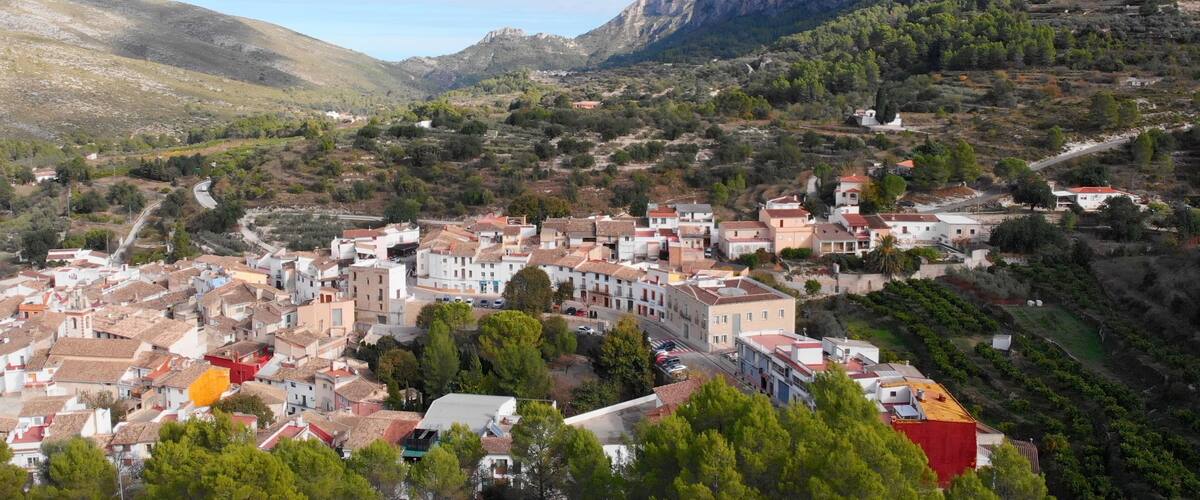 A town nestled in a valley with a mountain backdrop.