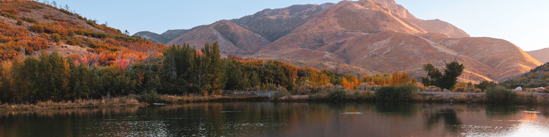 Panoramic view of reflections of hills in the Salt creek reservoir in Utah under evening light.