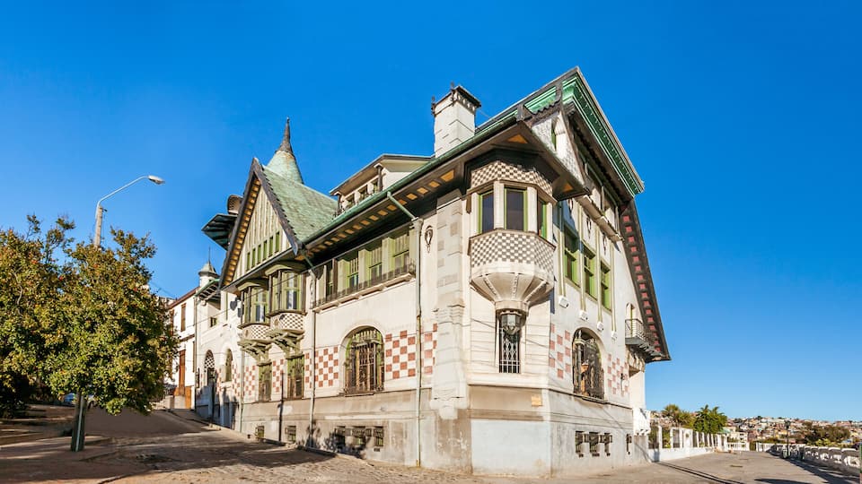A historic building with ornate architecture, a green roof, and a clear blue sky.