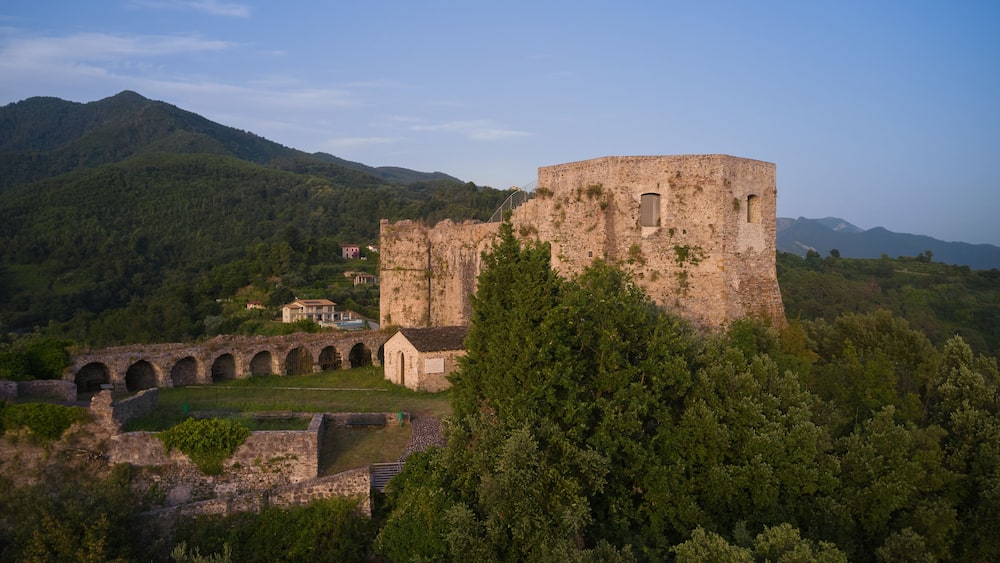 This high-resolution image showcases the historical castle against the stunning landscape. Capture the panoramic beauty of Aghinolfi Castle in Montignoso, Italy, through stunning drone photography.