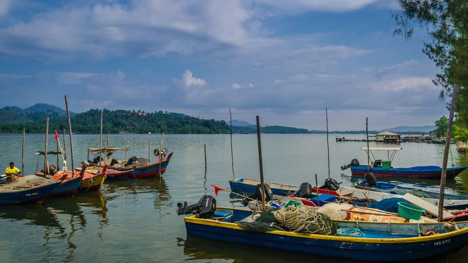 A calm lake with several small boats docked along the shore.