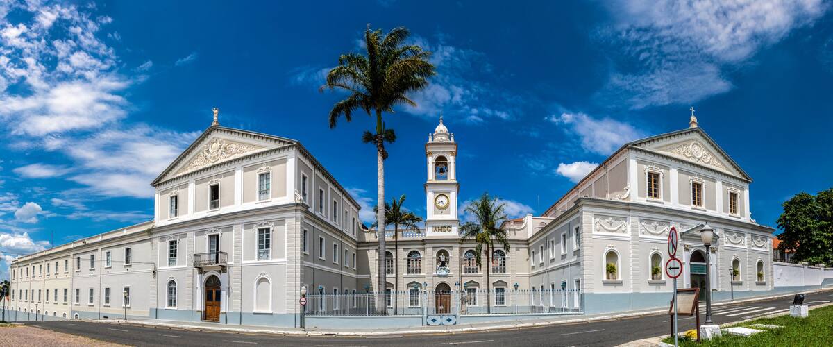 A historic building with two towers, a clock, and a palm tree.