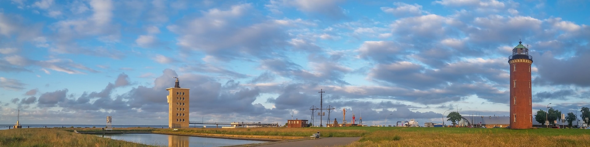 Un paisaje costero con un faro, una torre y una masa de agua tranquila.