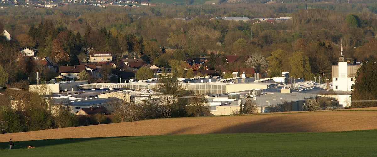 A town with houses, a large building, and surrounding hills.