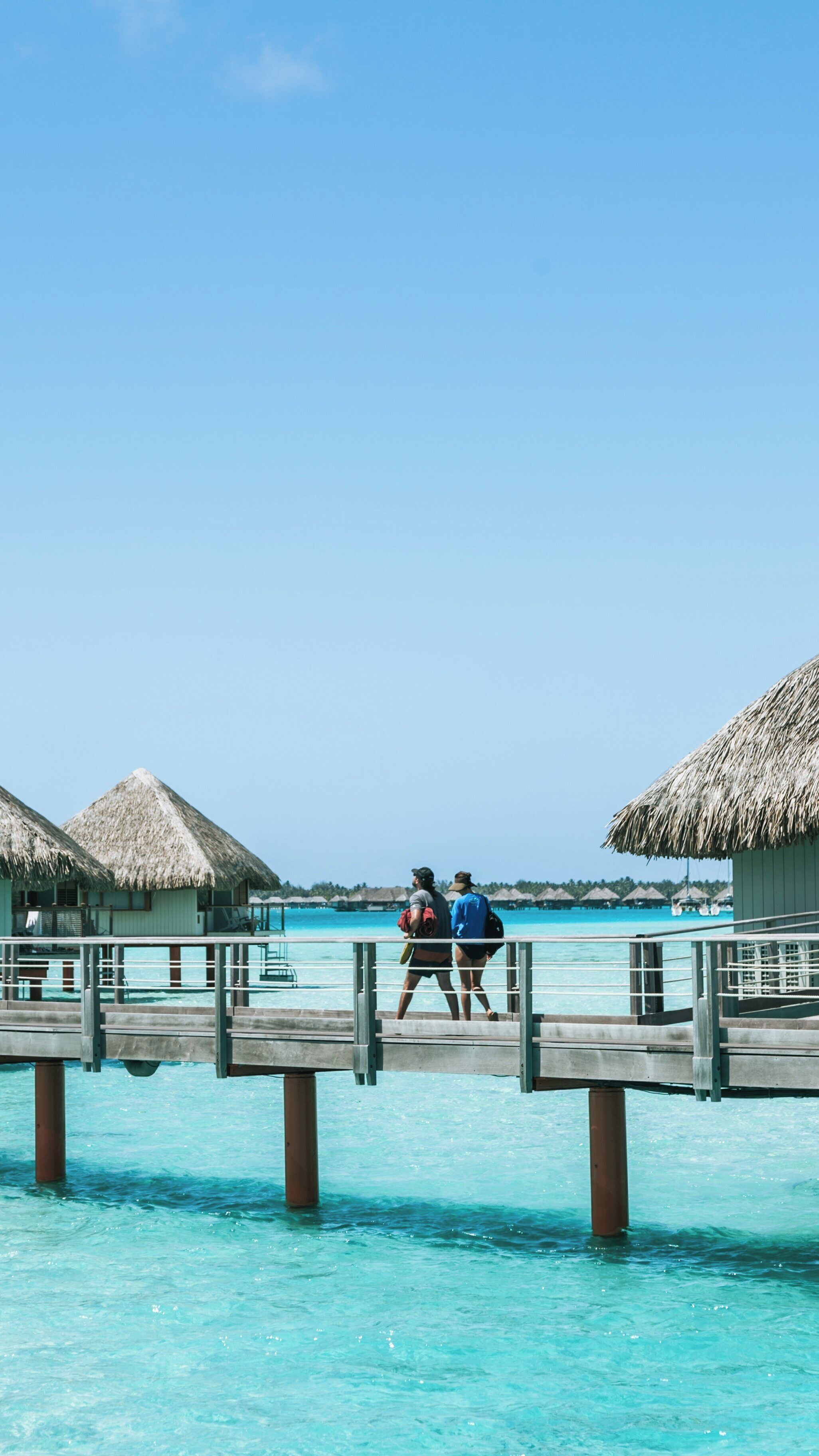 Couple walking along the pier at Le Meridien Beach in Bora Bora, enjoying the tropical paradise of the Leeward Islands in French Polynesia