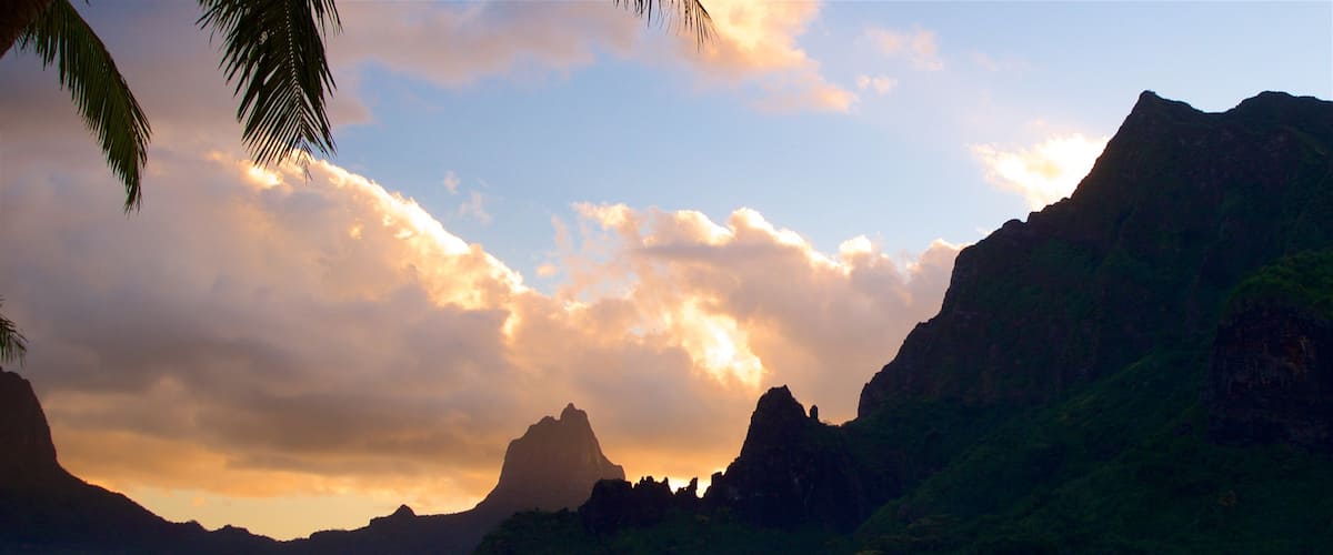 A sunset over a mountainous landscape with a body of water in the foreground.