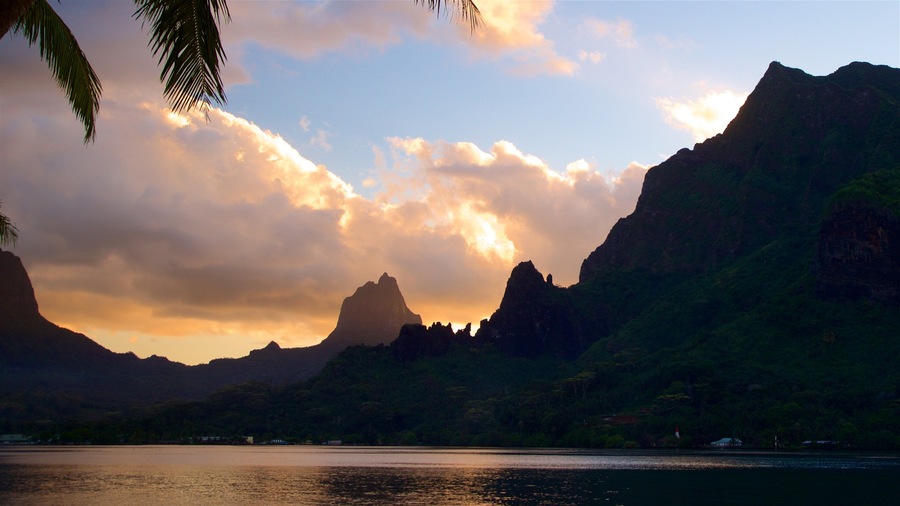Un atardecer sobre un paisaje montañoso, con una masa de agua al frente.
