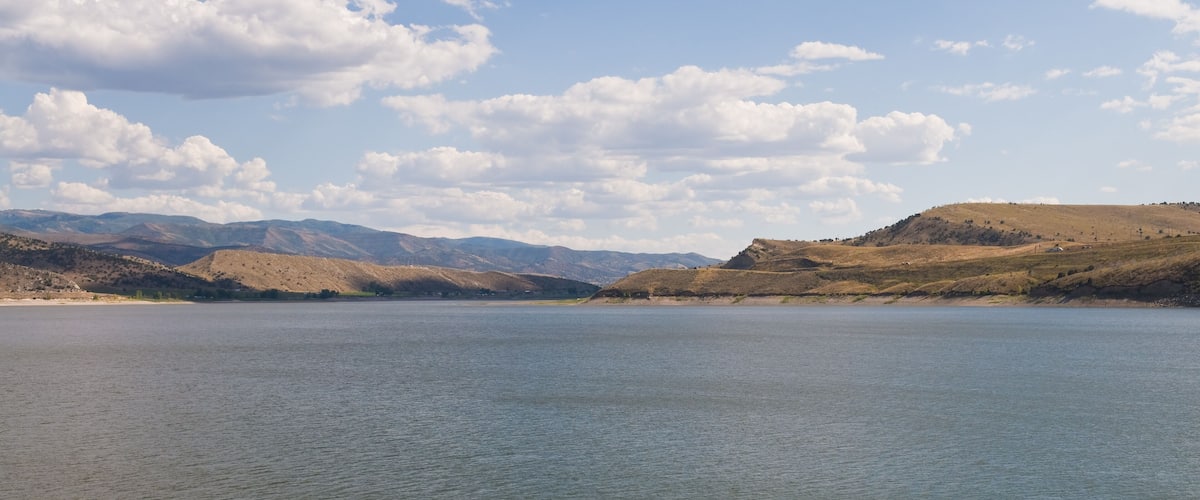 A calm lake with hills in the background and a clear sky.