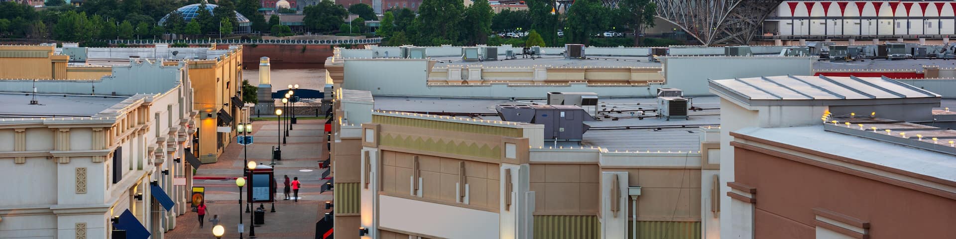 A cityscape at sunset with modern buildings and a historic bridge.