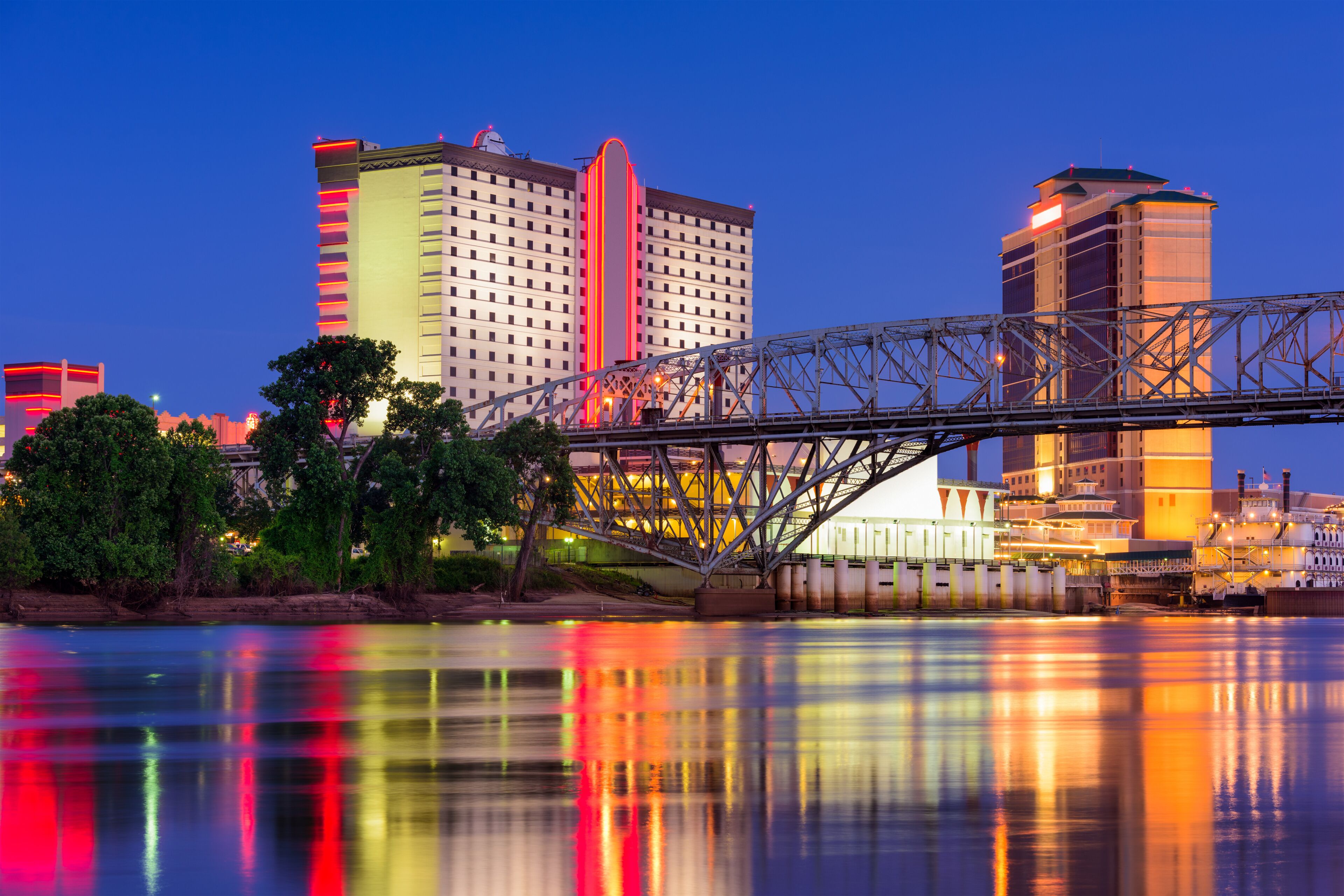 A bridge over a river with reflections of buildings and trees.