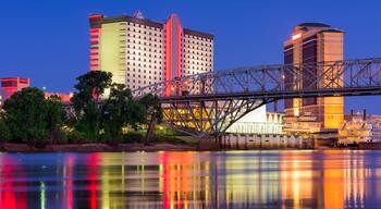 A bridge over a river with reflections of buildings and trees.