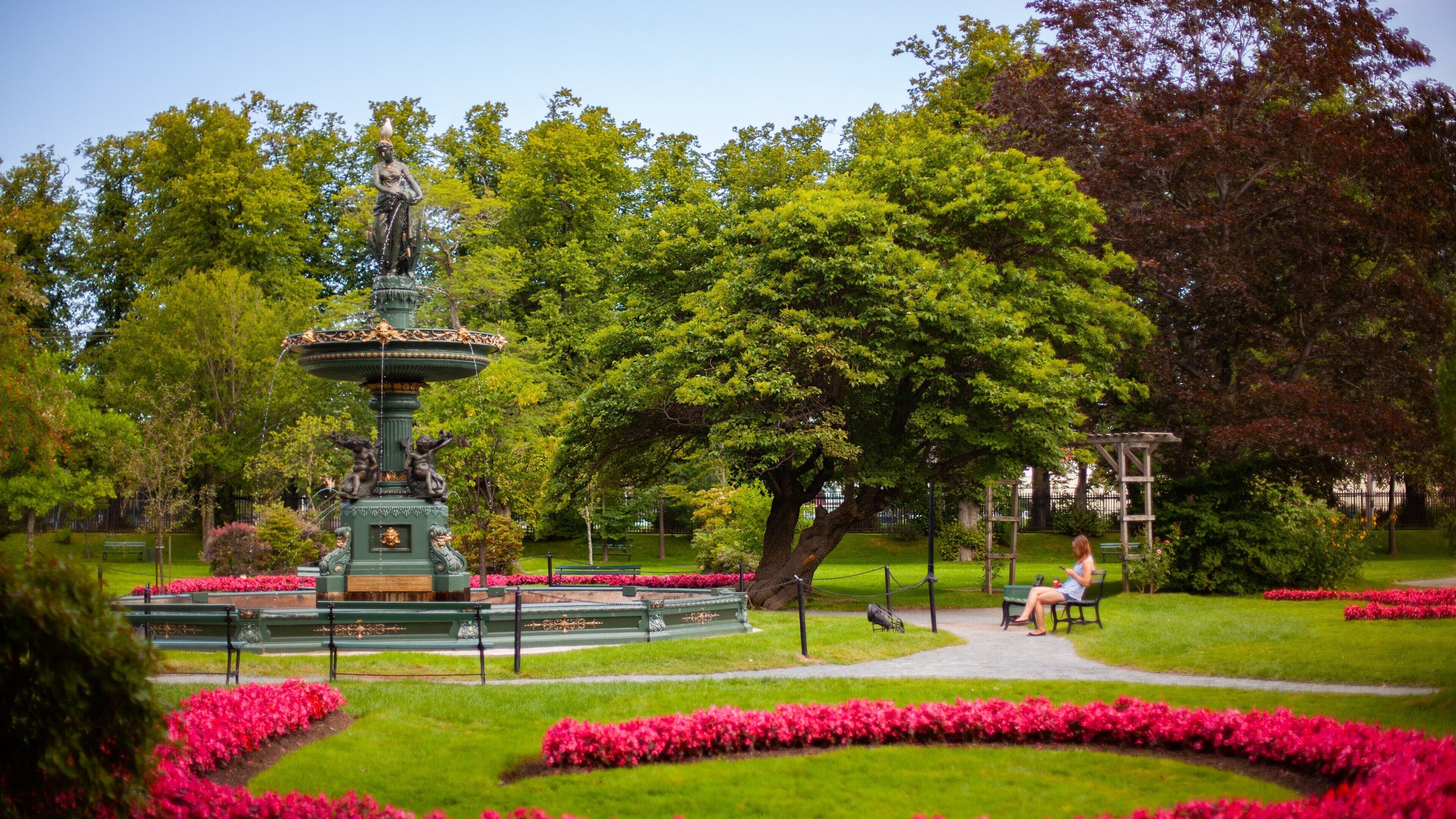 A park with a fountain, benches, and blooming flowers.