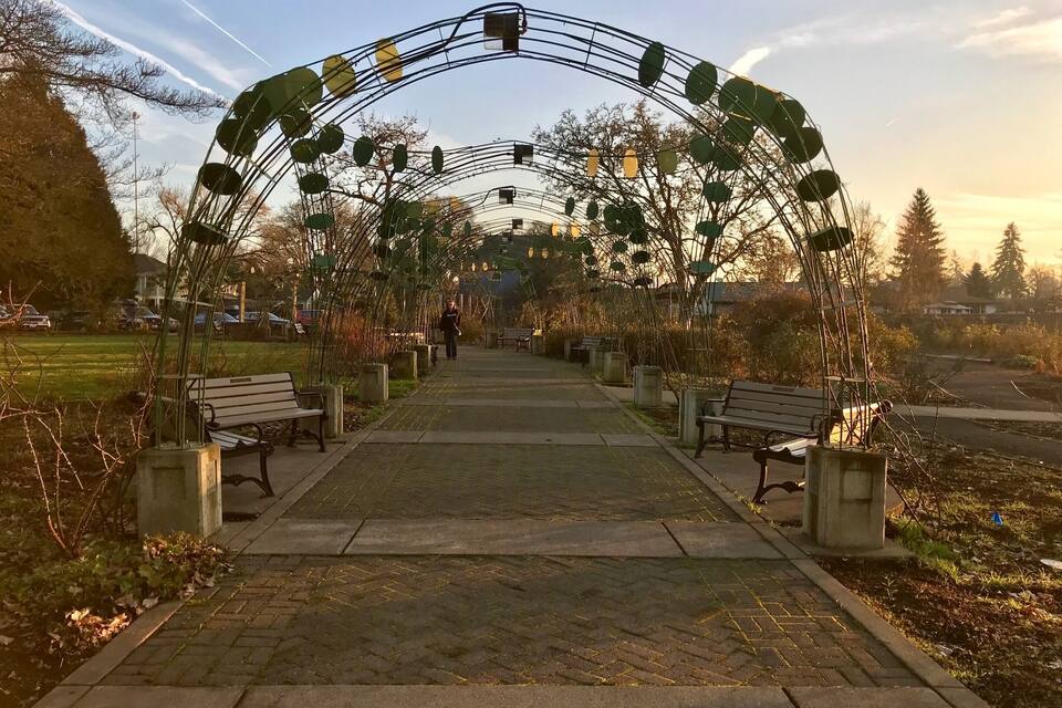 A park pathway with benches and an archway.