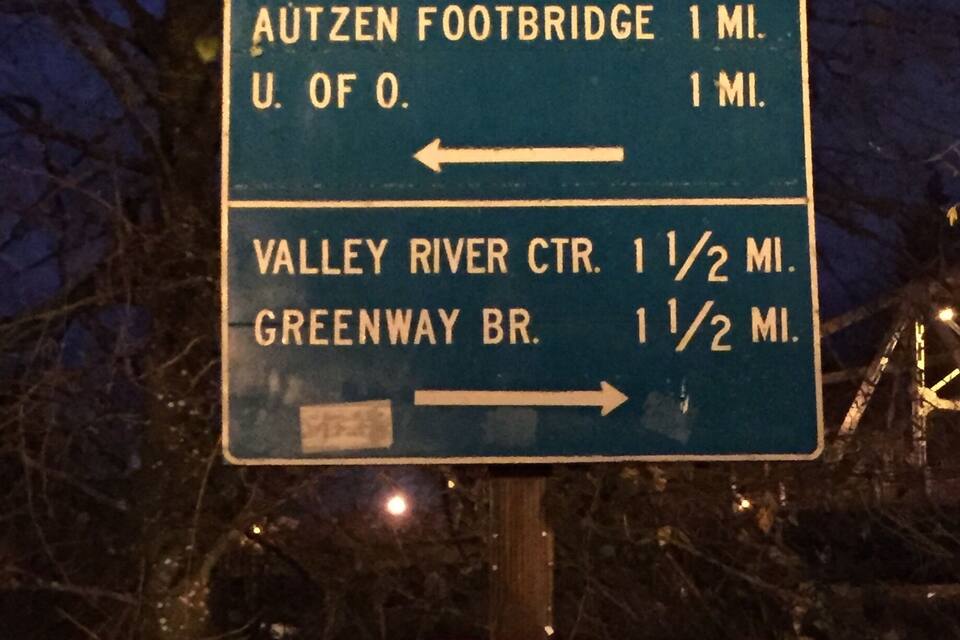 Hinweisschild für den North Bank Trail mit Entfernungen zur Autzen Footbridge, zur Universität von Oregon, zum Valley River CTR und zur Greenway BR.