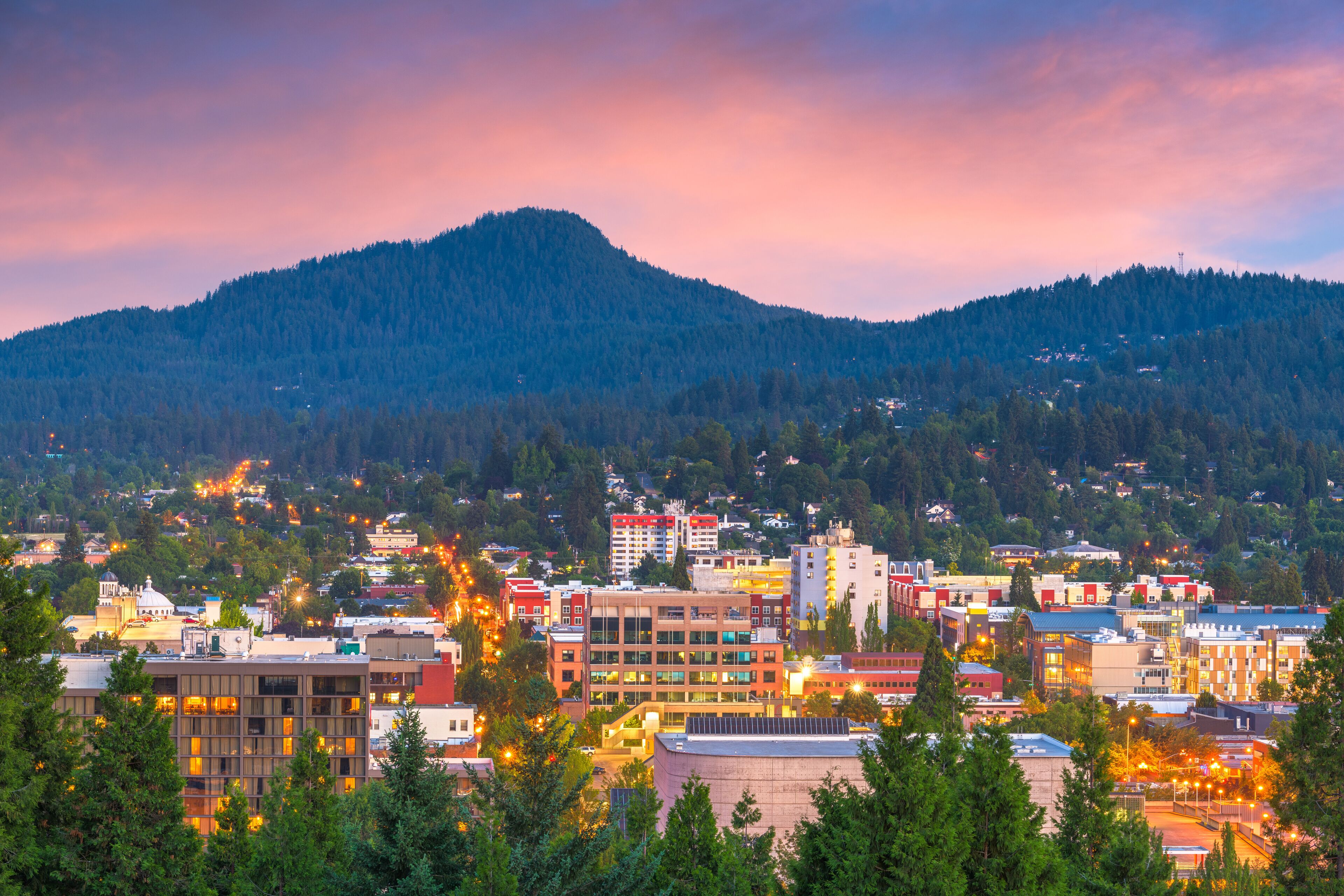 A cityscape with a mountain in the background and a mix of modern and older buildings.