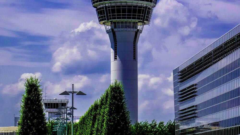 A control tower with a modern building beside it.