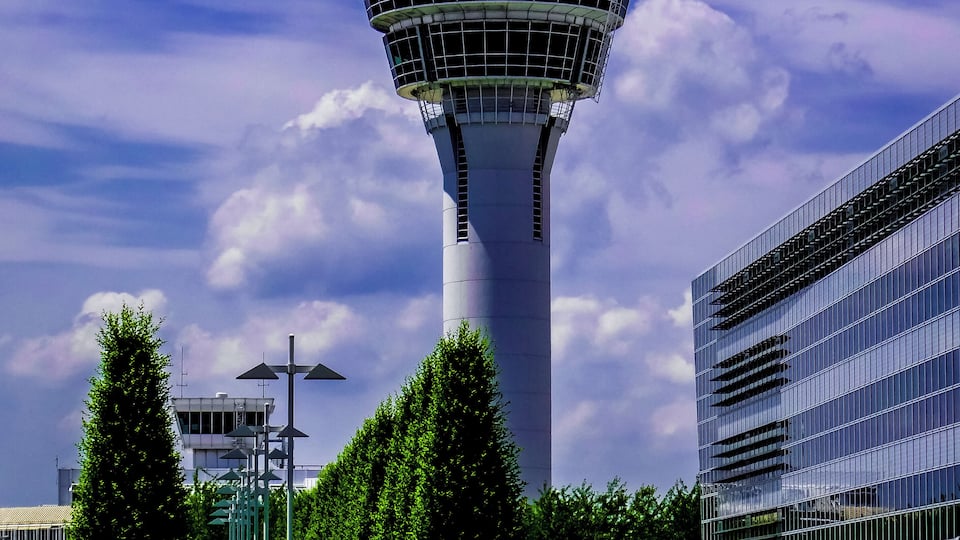 A control tower with a modern building beside it.