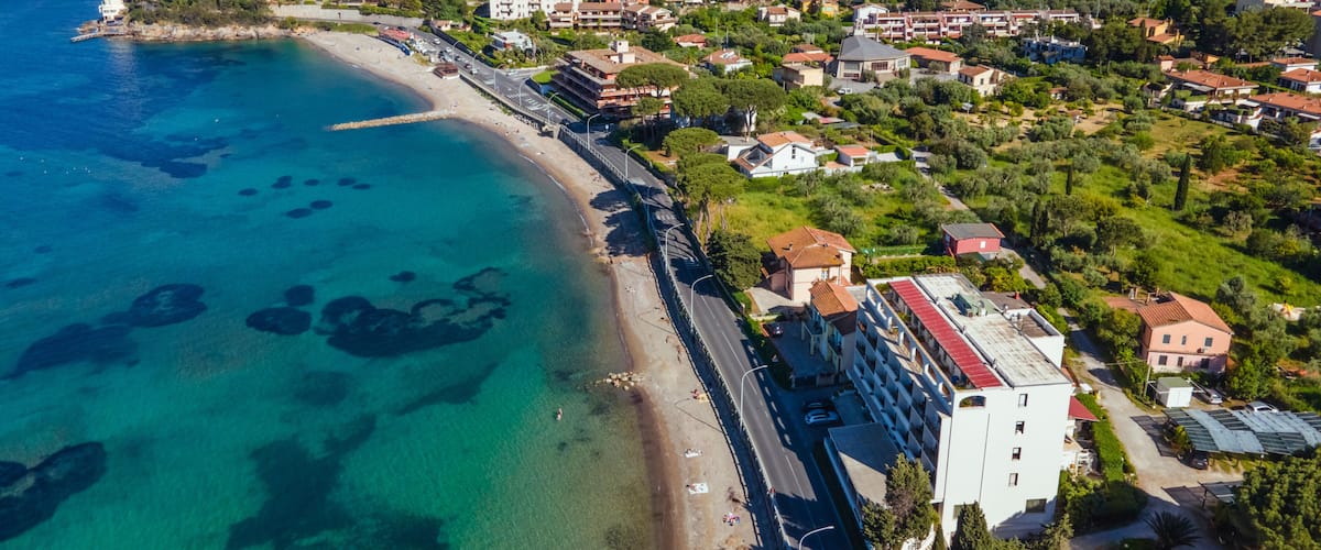 Uma cidade costeira com mar azul cristalino, uma praia e edifícios residenciais.