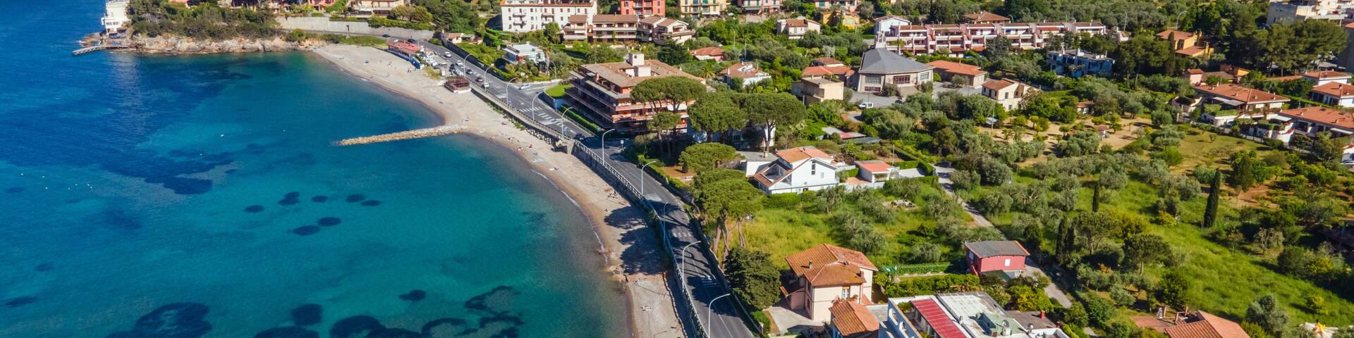 A coastal town with a clear blue sea, a beach, and residential buildings.
