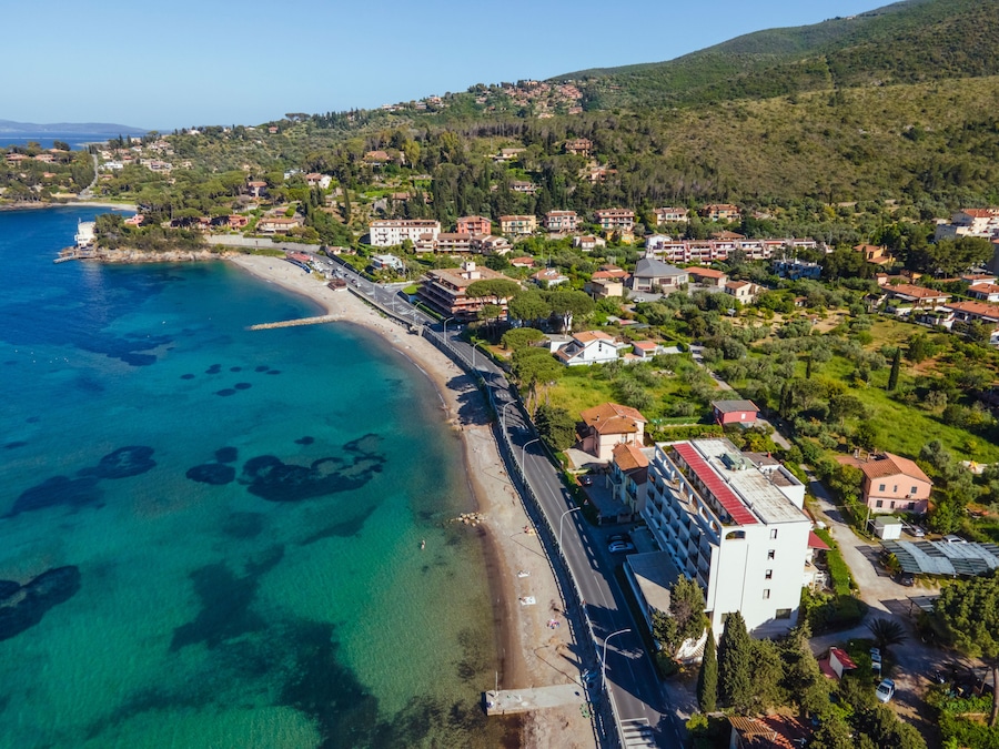Un pueblo costero con un mar azul cristalino, una playa y edificios residenciales.