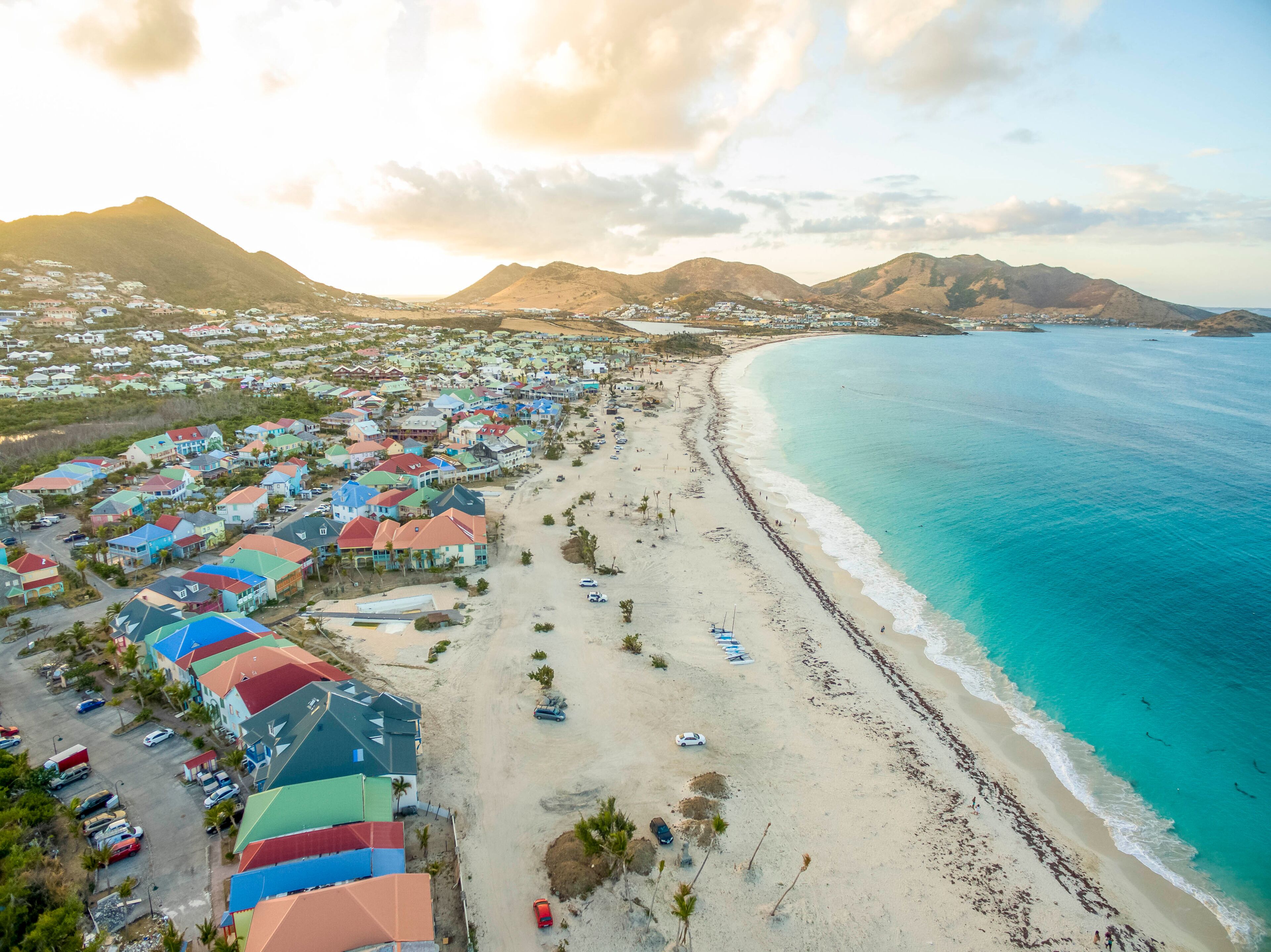 A coastal town with colorful houses, a sandy beach, and a clear blue ocean.