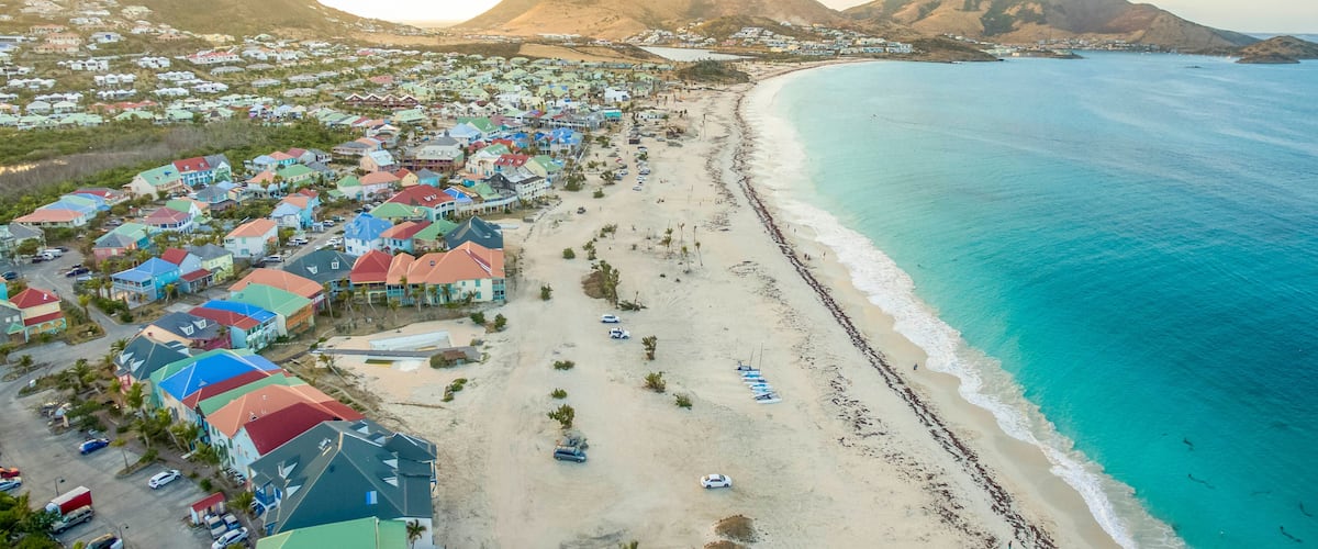 Un pueblo costero con casas coloridas, una playa de arena y un océano azul cristalino.