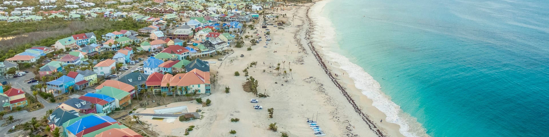 A coastal town with colorful houses, a sandy beach, and a clear blue ocean.
