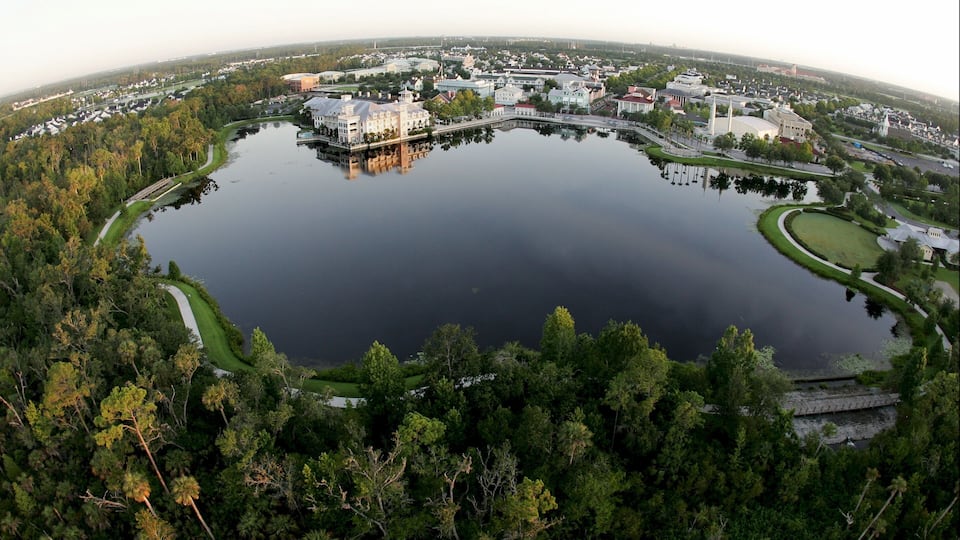 A large lake surrounded by dense forest and a mix of residential and commercial buildings.