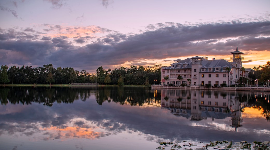 A hotel in Celebration (Orlando, Kissimmee), Florida reflects at the edge of a small lake during sunset with interesting cloud formations above.