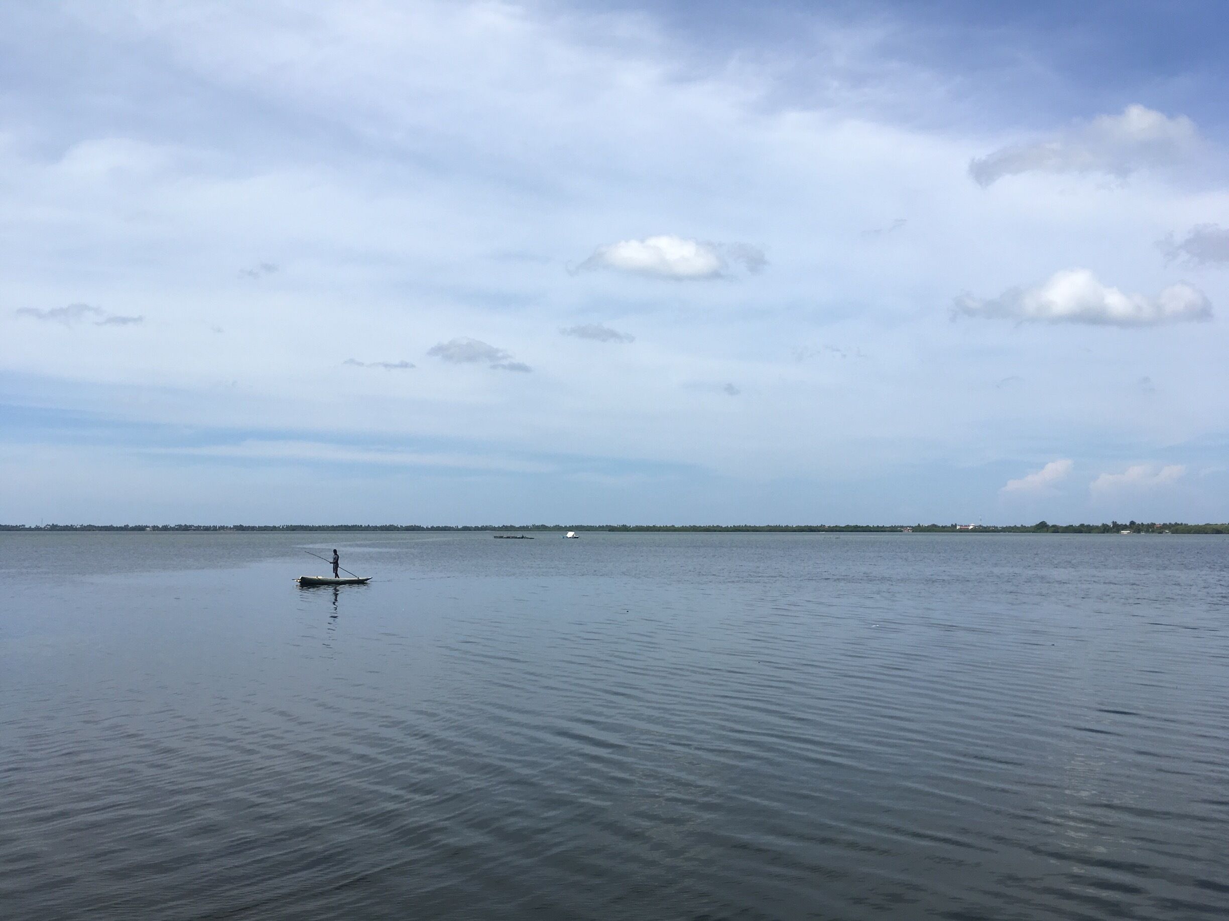 A calm body of water with a person paddling a small boat.