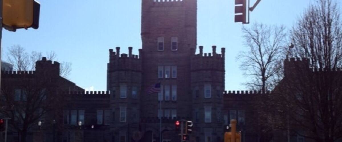 A castle-like building with a tall tower, traffic lights, and a crosswalk.