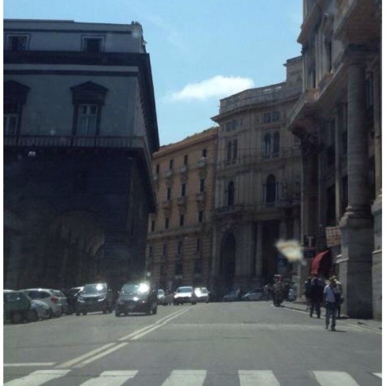 A street with parked cars and pedestrians.
