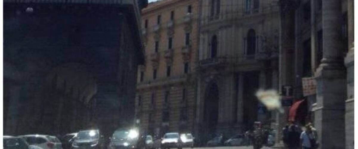 A street with parked cars and pedestrians.