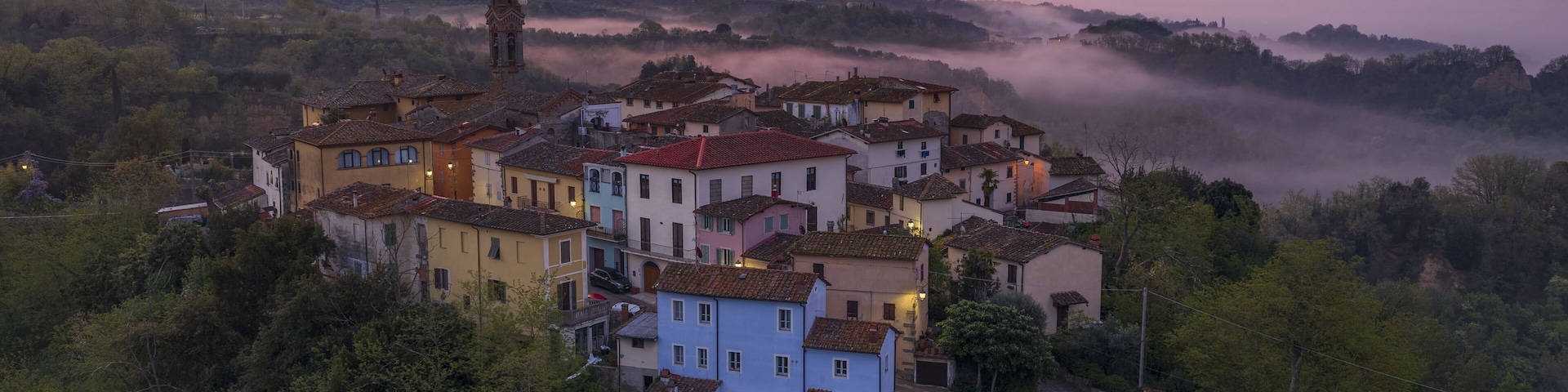Aerial view of the historic village of Botriolo and Le Balze del Valdarno with colorful houses and morning mist in the valley under a pink sunrise sky Botriolo, Toscana, Italy.