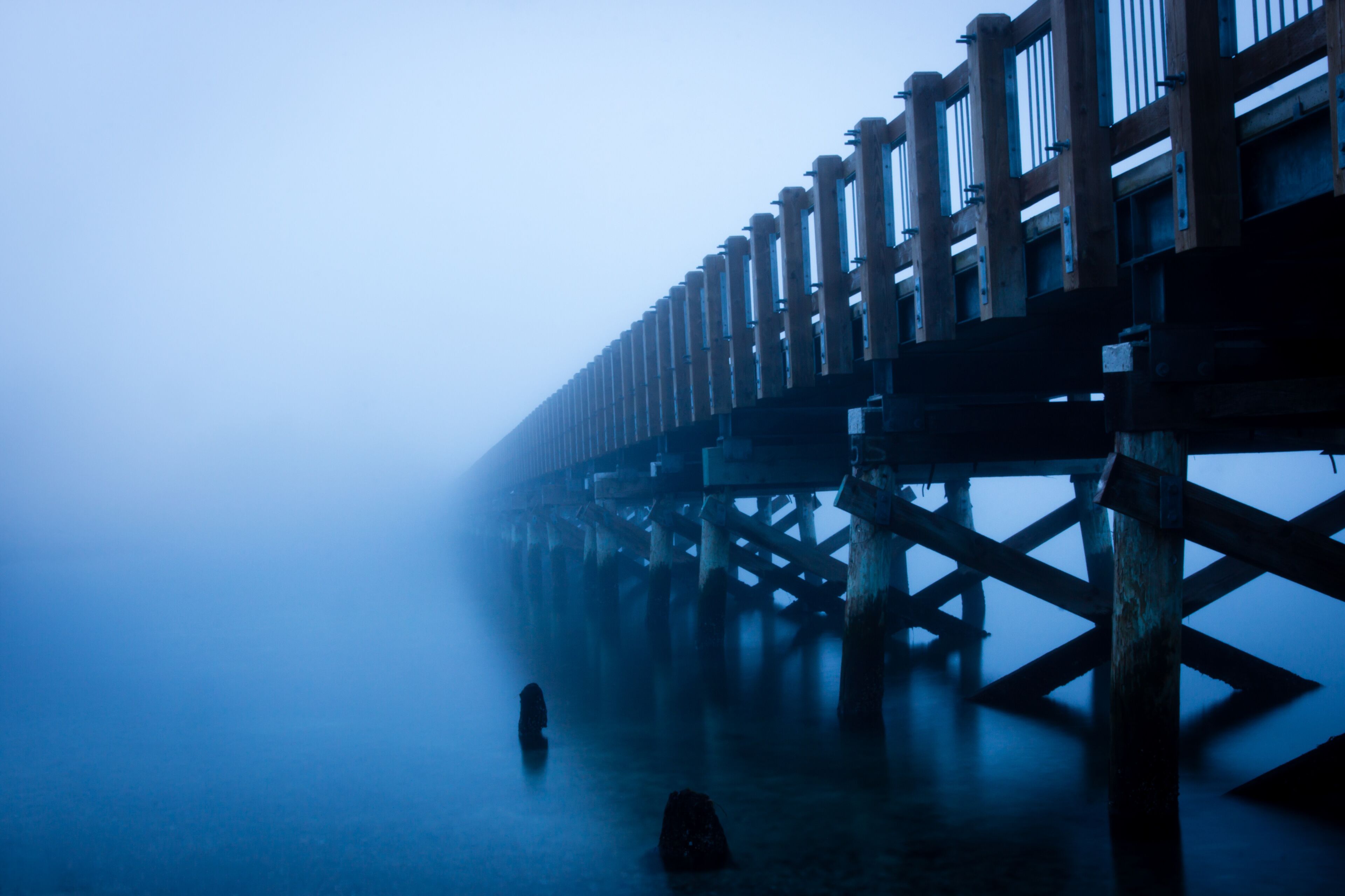 A foggy pier with wooden railings and a foggy atmosphere.