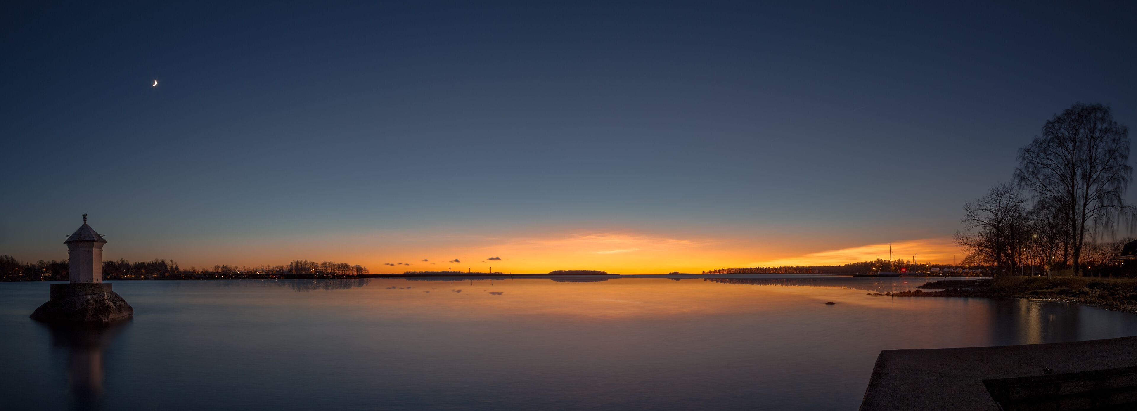 panorama with a little lighthouse in a lake during sunset
