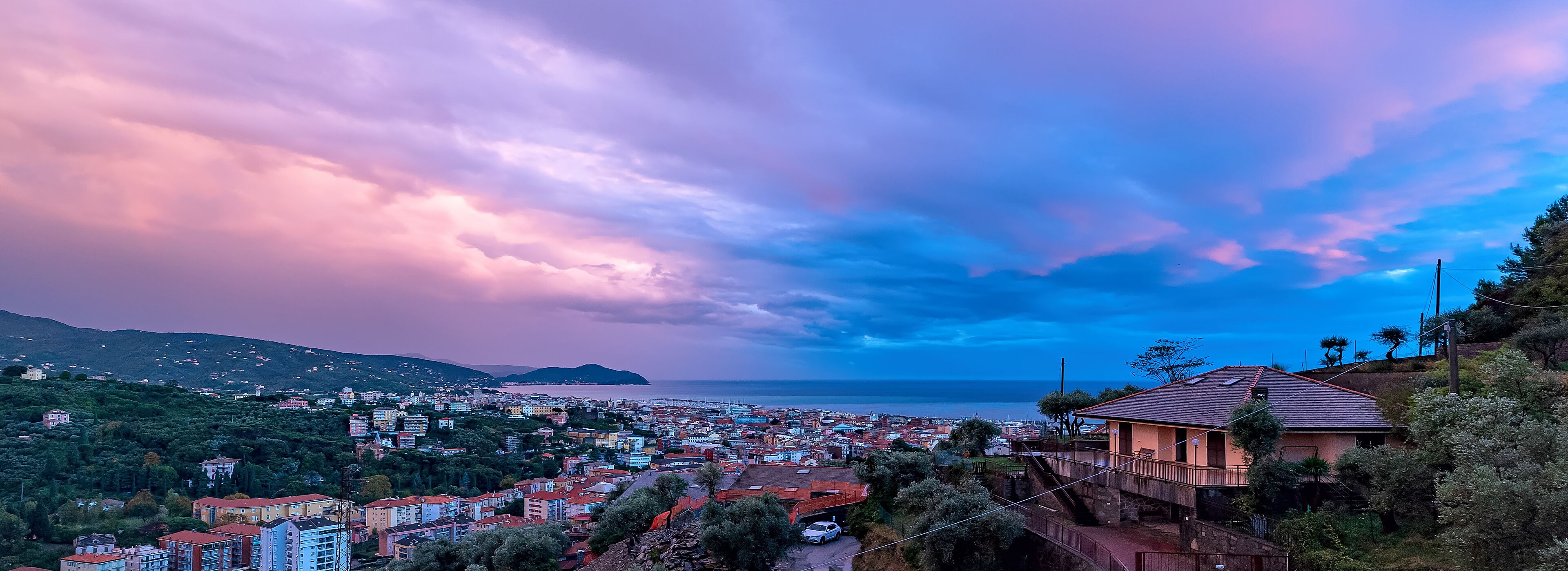 A coastal town with a view of the sea and mountains in the background.