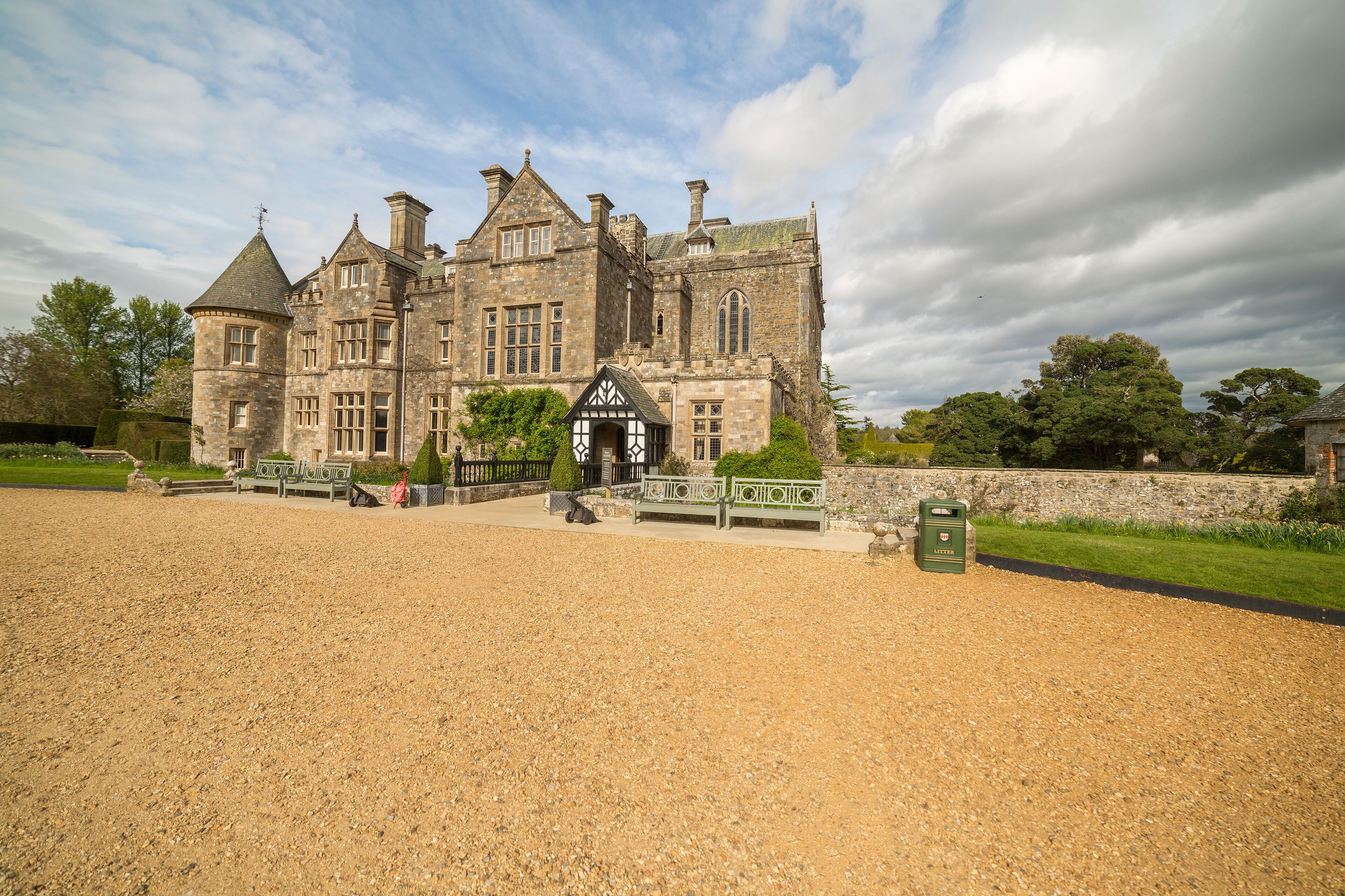 A large stone building with a traditional architectural style, featuring multiple chimneys and a prominent entrance with a small porch.
