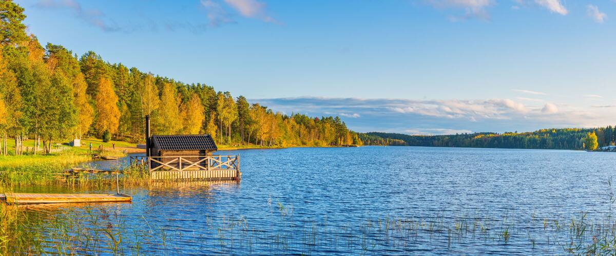 A wooden dock on a calm lake surrounded by autumn-colored trees.